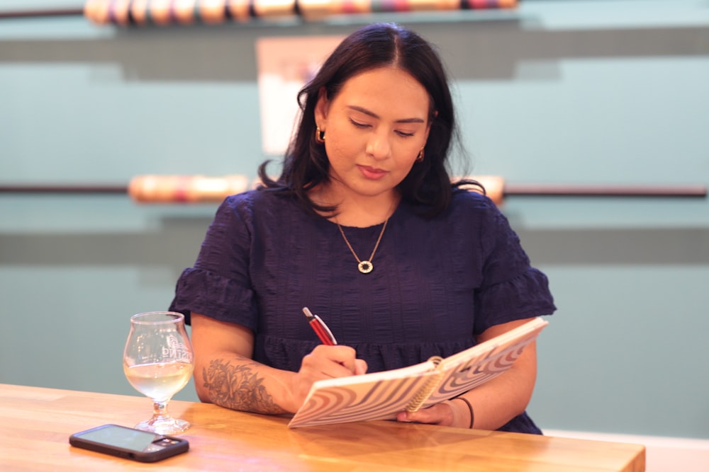 a woman sitting at a table writing on a piece of paper