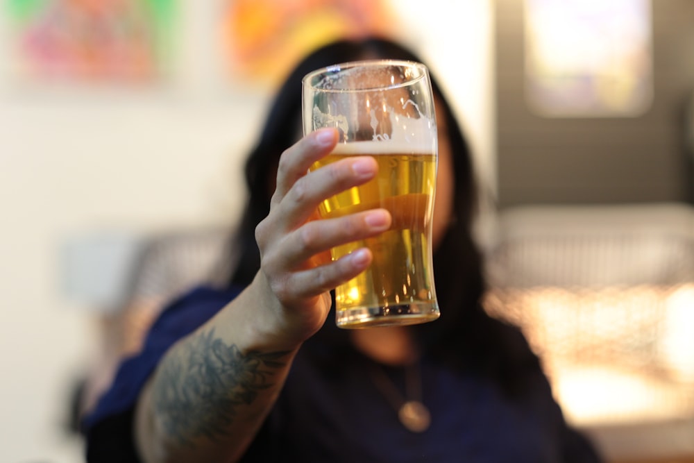 a woman holding a glass of beer in her hand