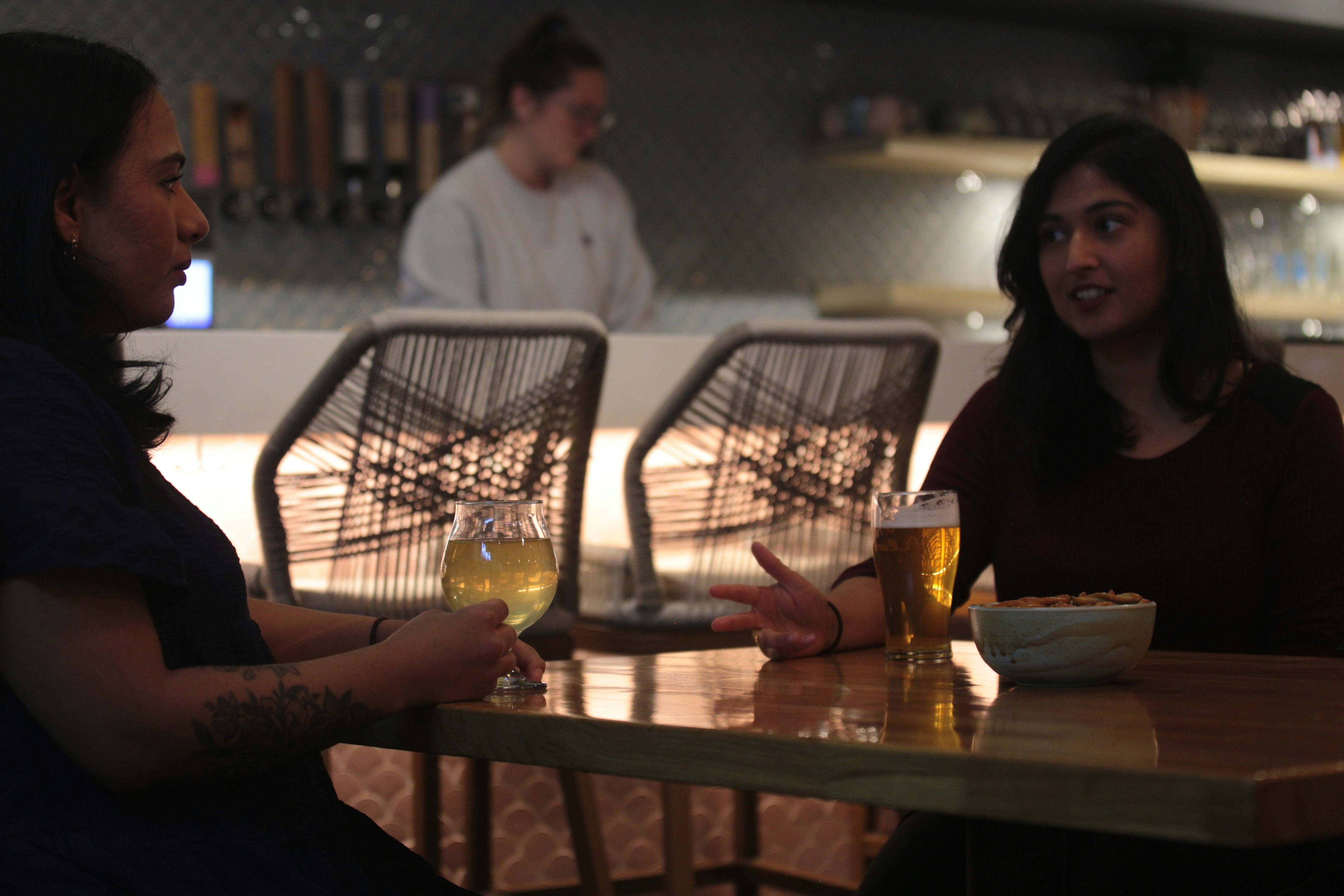 a couple of women sitting at a table with glasses of wine