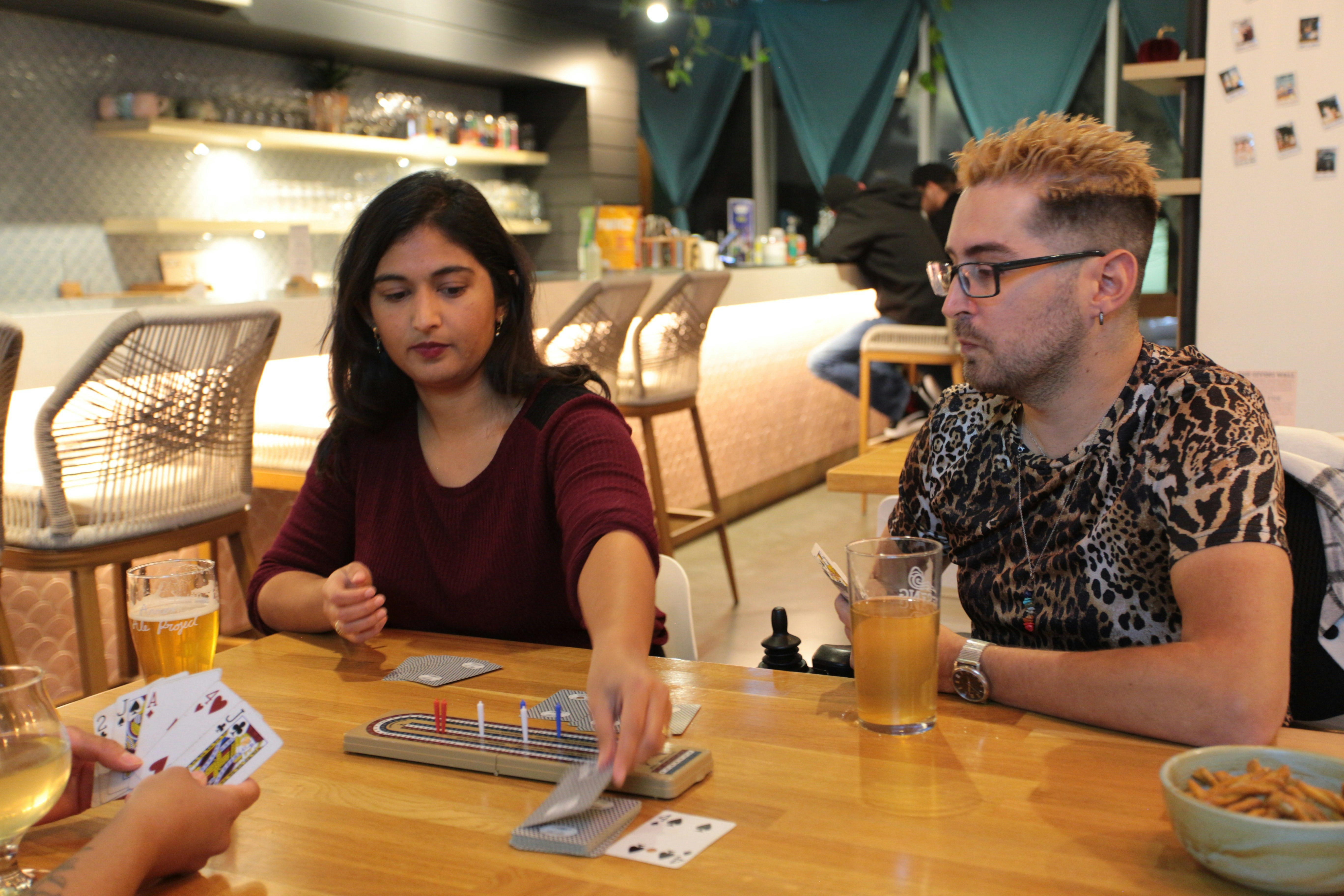 two couples playing a card game like Bridge at a table - brain games for seniors