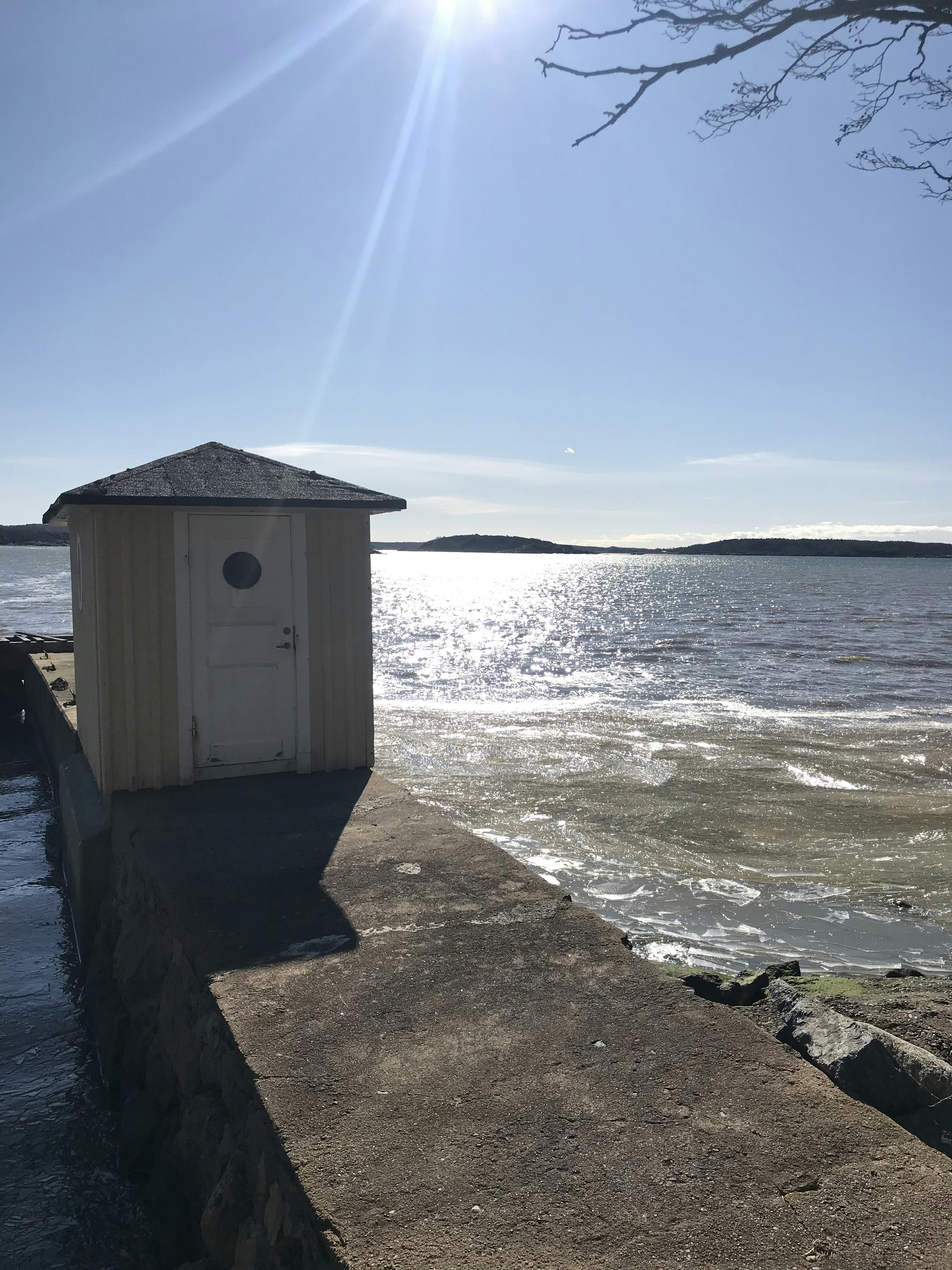 a small outhouse sitting on the side of a body of water