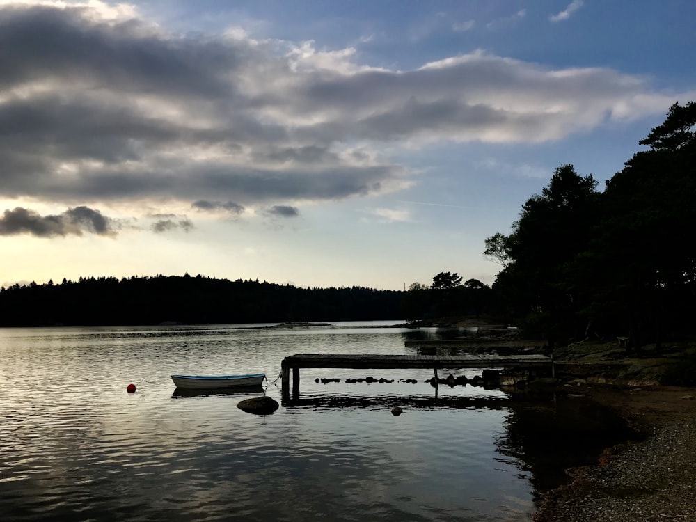 a boat sitting on top of a lake next to a dock