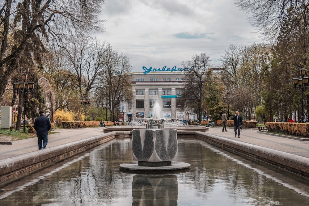 a fountain in a park with people walking around