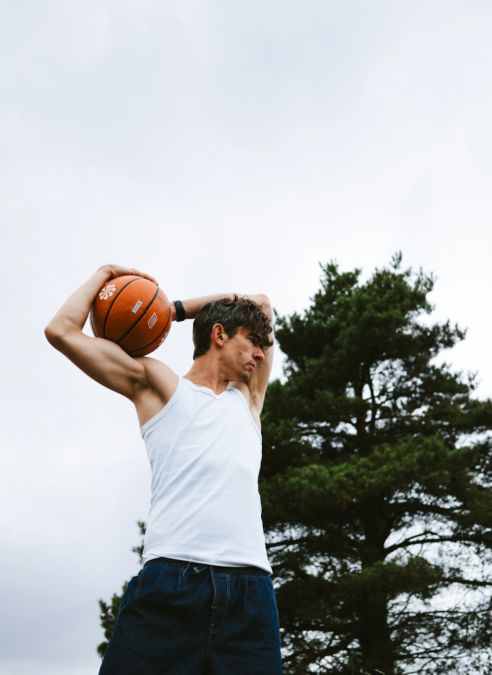 Un hombre sosteniendo una pelota de baloncesto en su cabeza