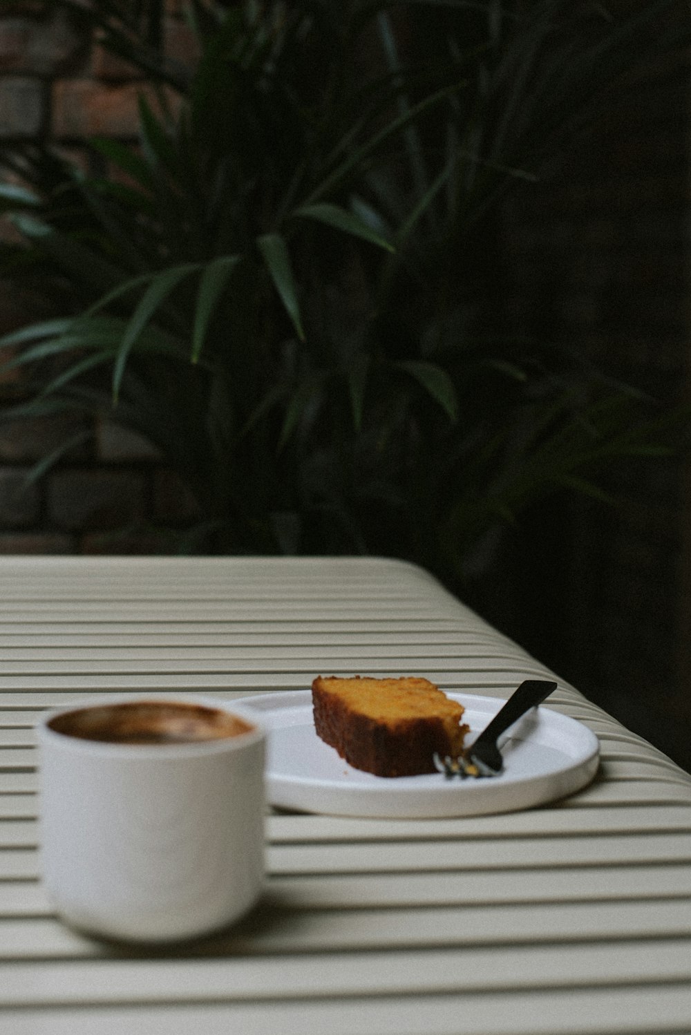 una fetta di torta su un piatto accanto a una tazza di caffè