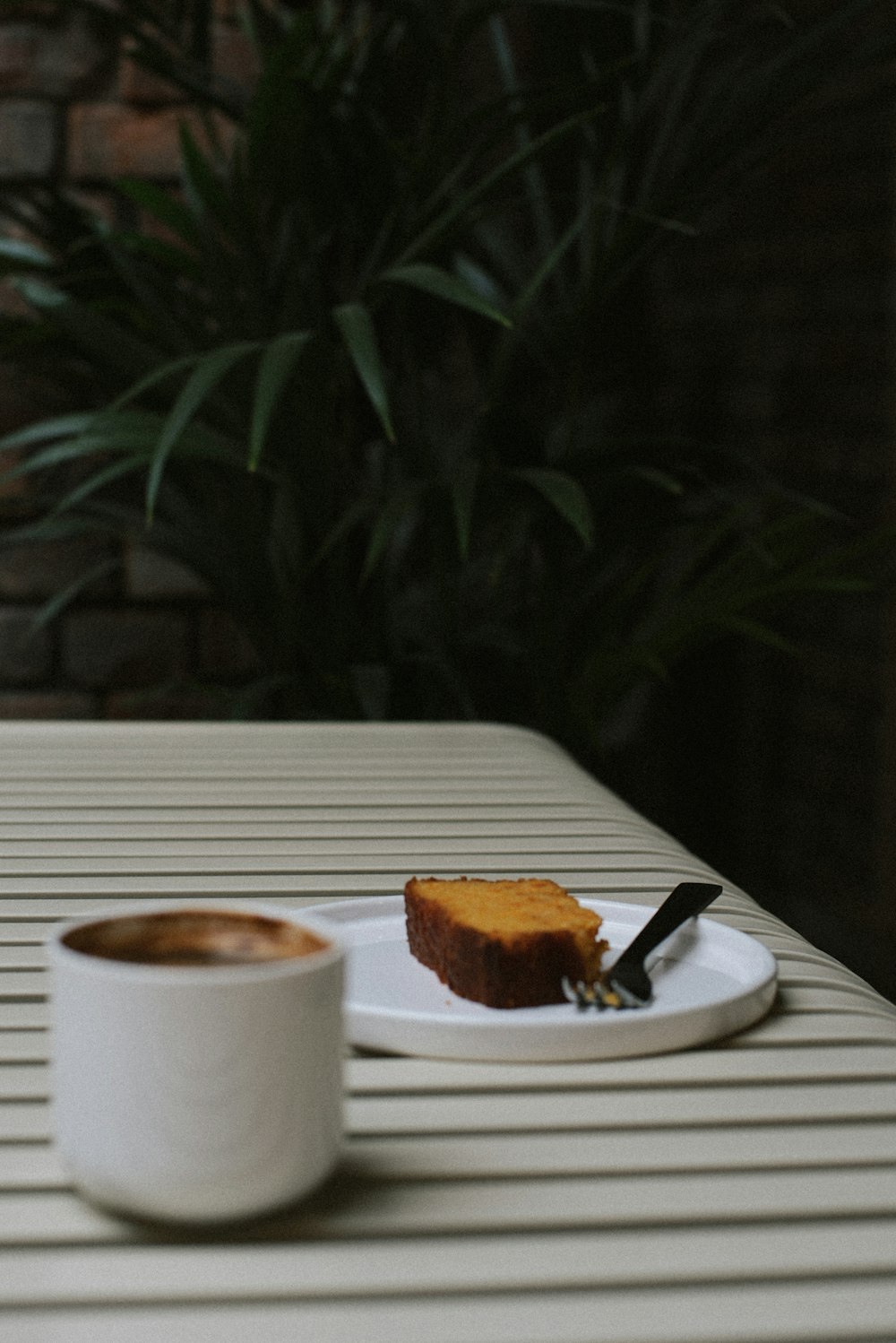 a piece of cake on a plate next to a cup of coffee