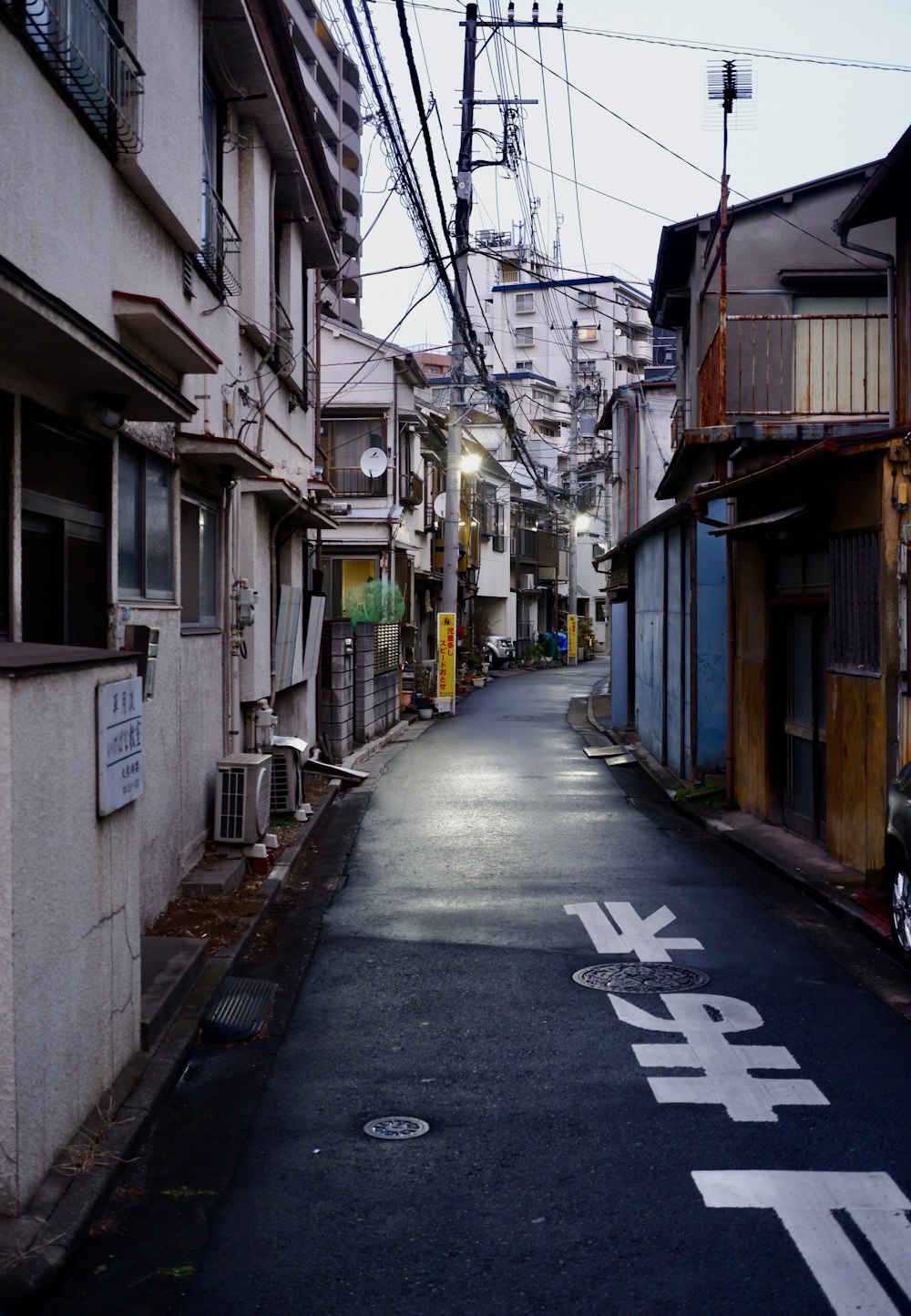 a narrow street with buildings and power lines above it
