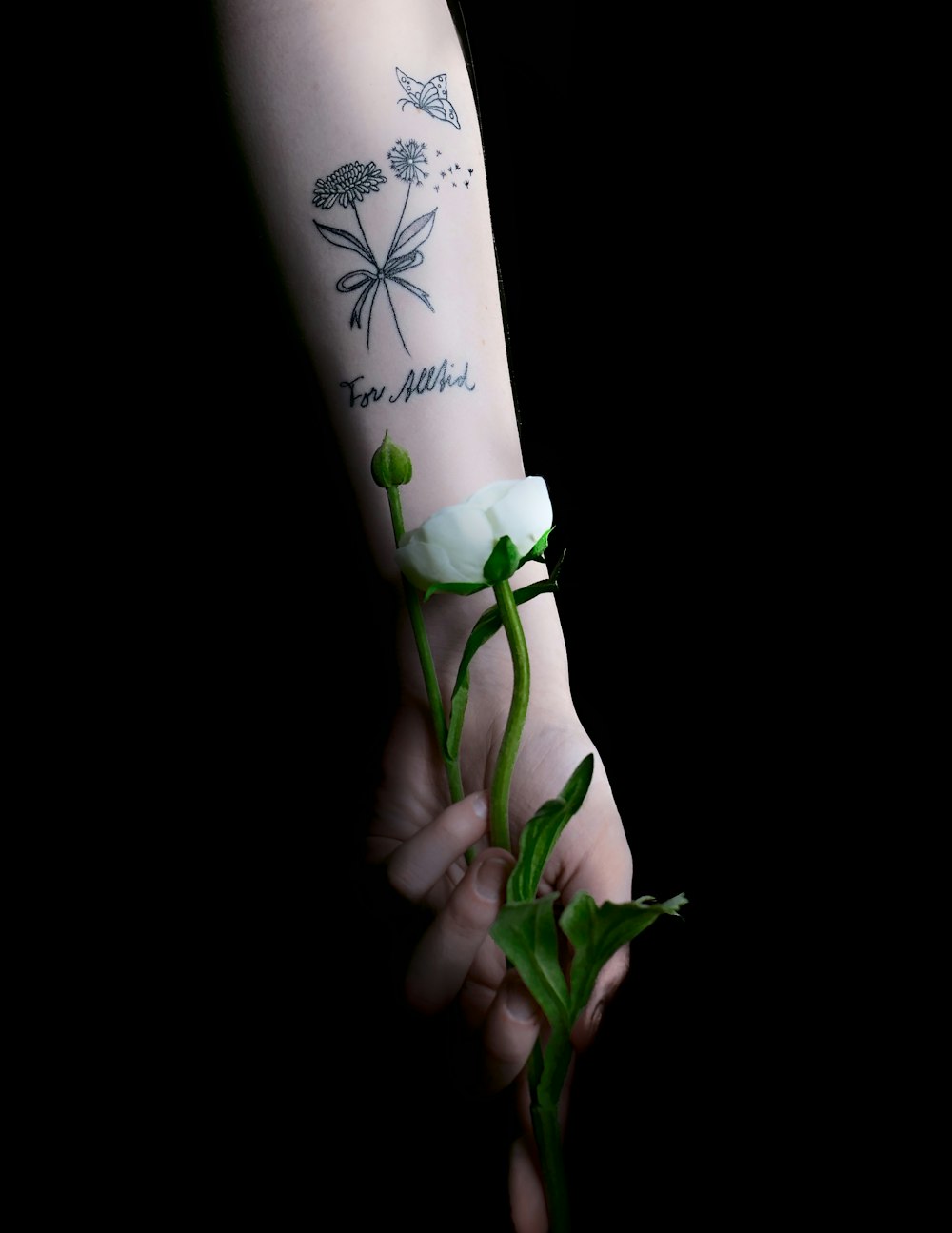 uma pessoa com uma tatuagem no braço segurando uma flor