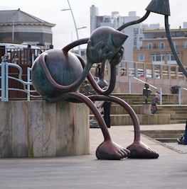 a statue of an alien sitting on top of a cement block