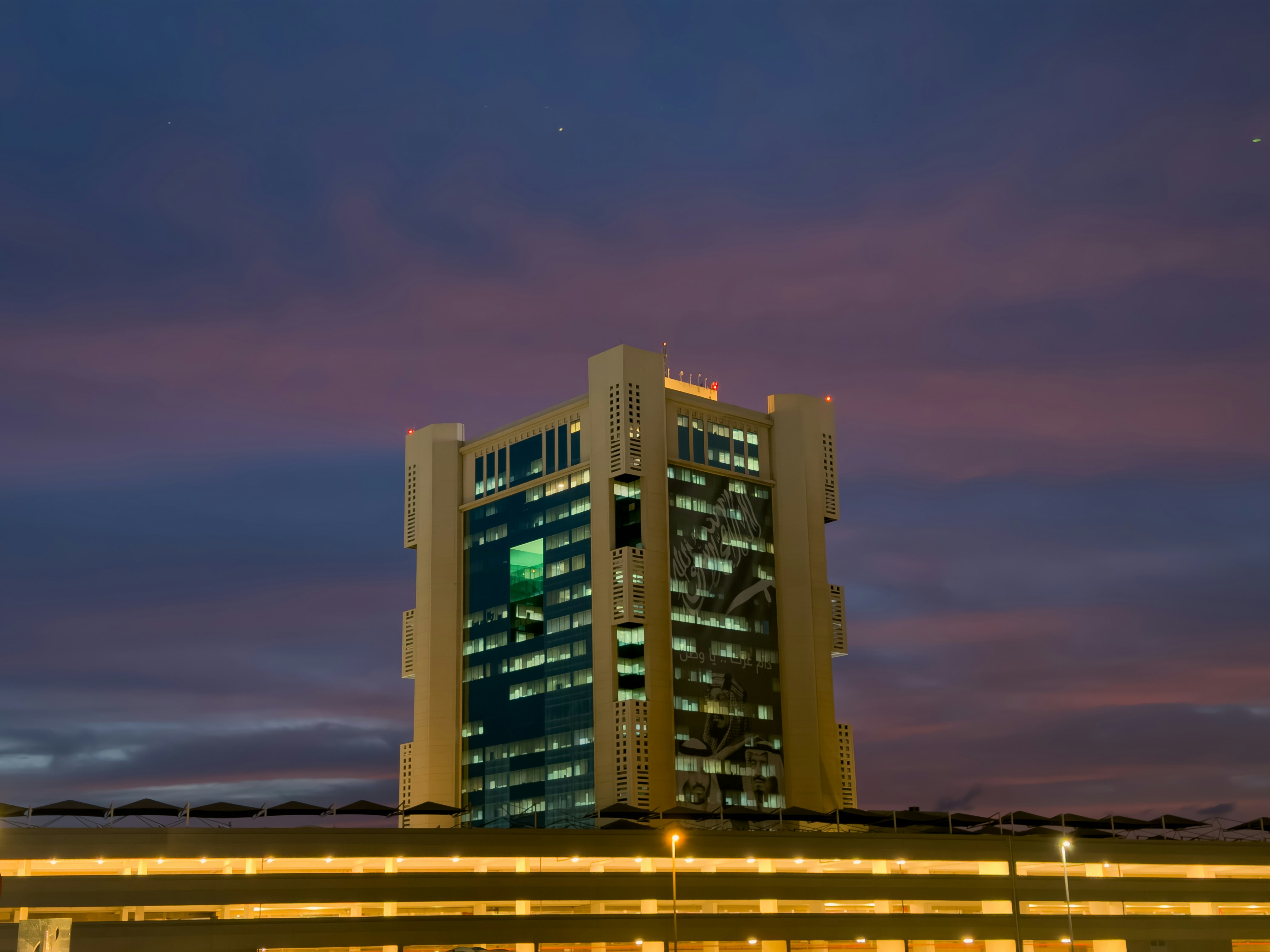 Modern Atlanta corporate office building exterior at dusk, dark shadows, deep blue sky, dramatic low-key lighting
