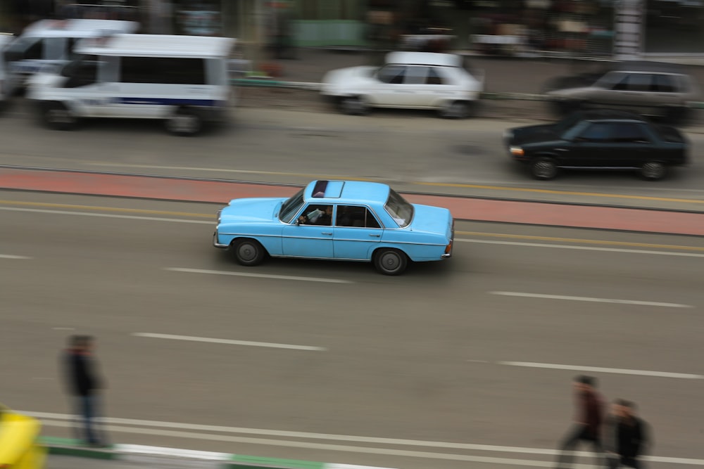 a blue car driving down a city street