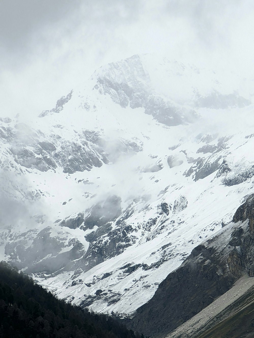 a mountain covered in snow and clouds in the distance