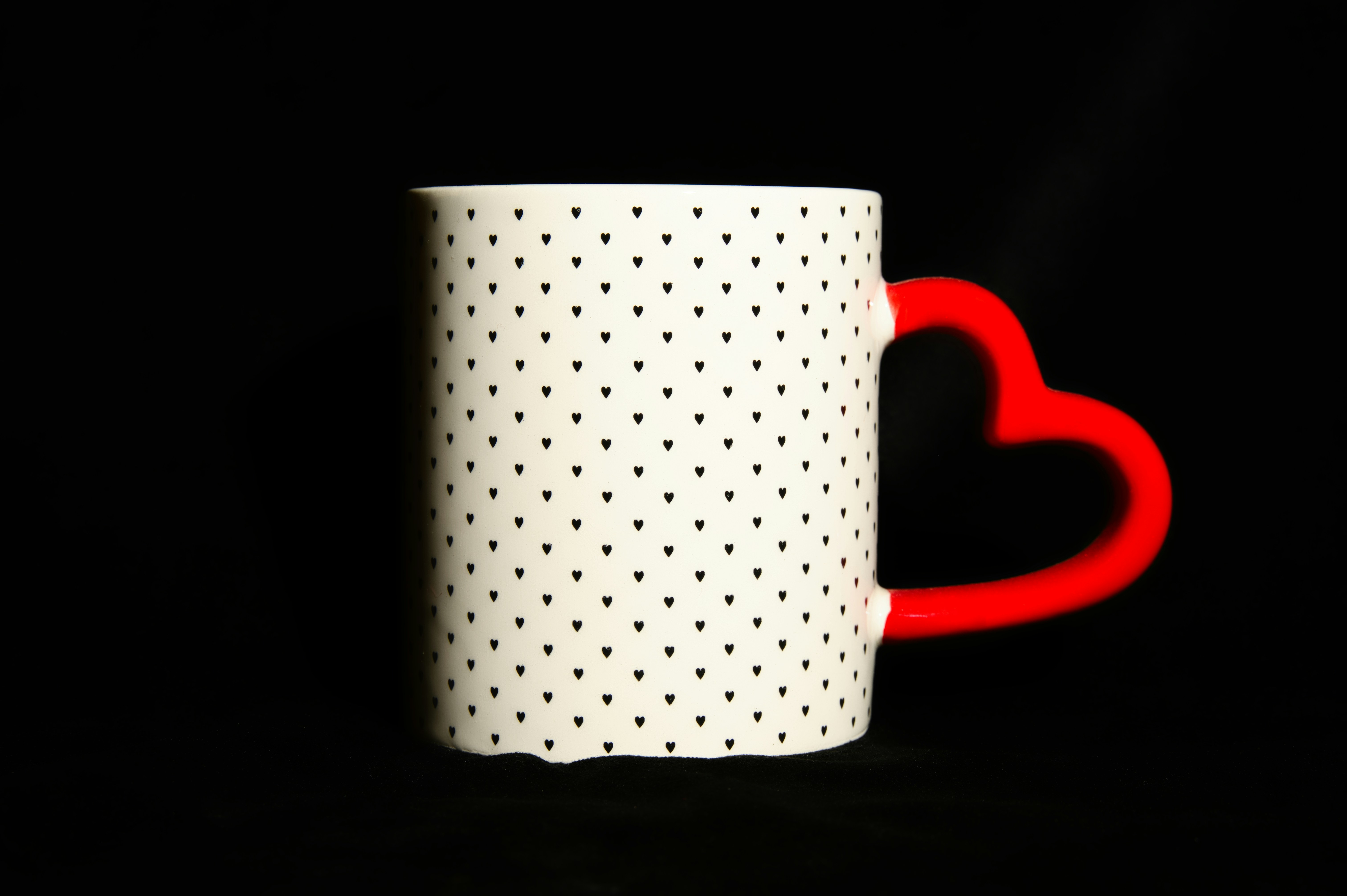 a white and red coffee mug with a heart on it