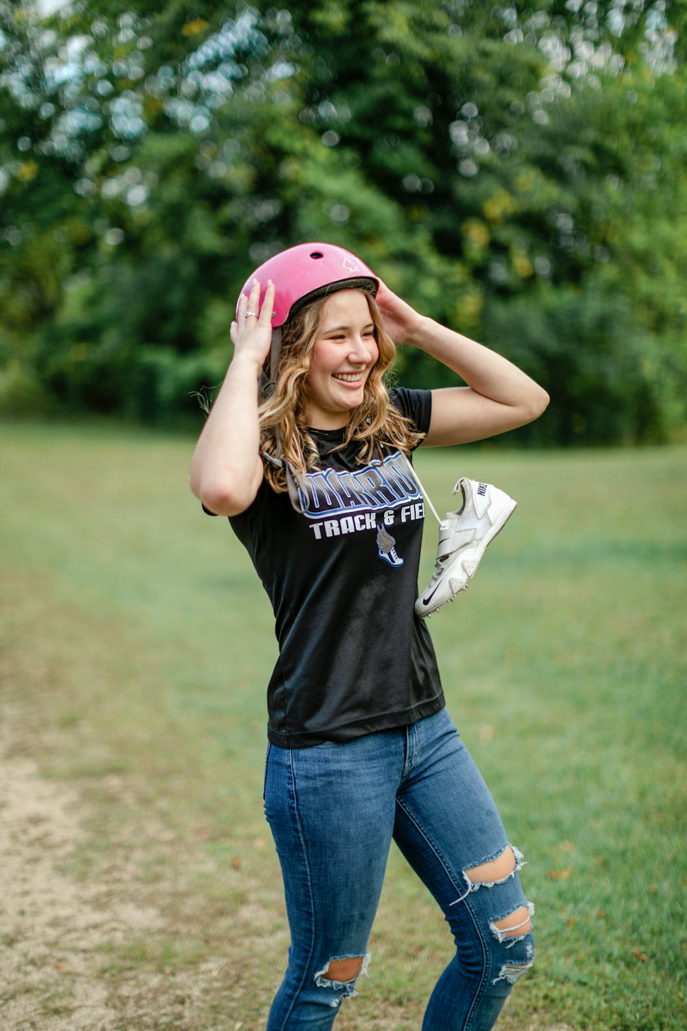 a woman wearing a pink helmet standing in a field