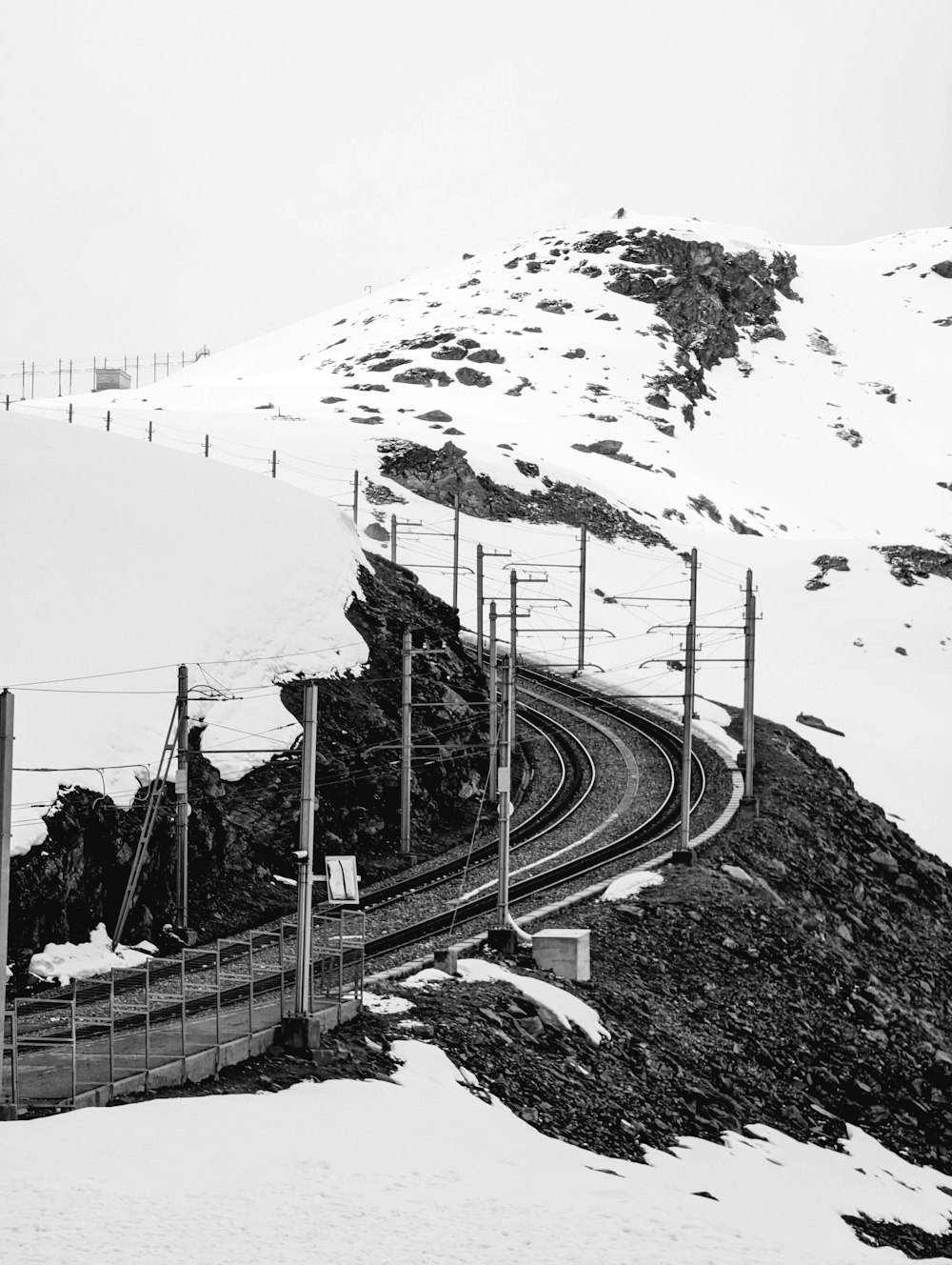 Una foto in bianco e nero di un binario del treno nella neve