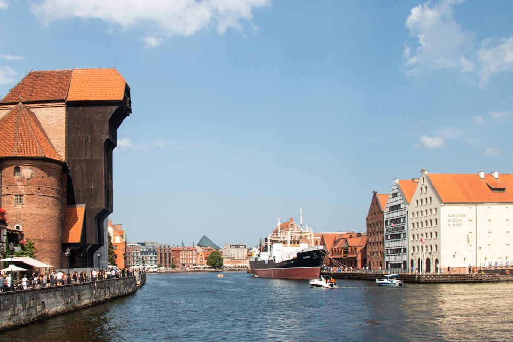 a river with a boat in the water and buildings in the background