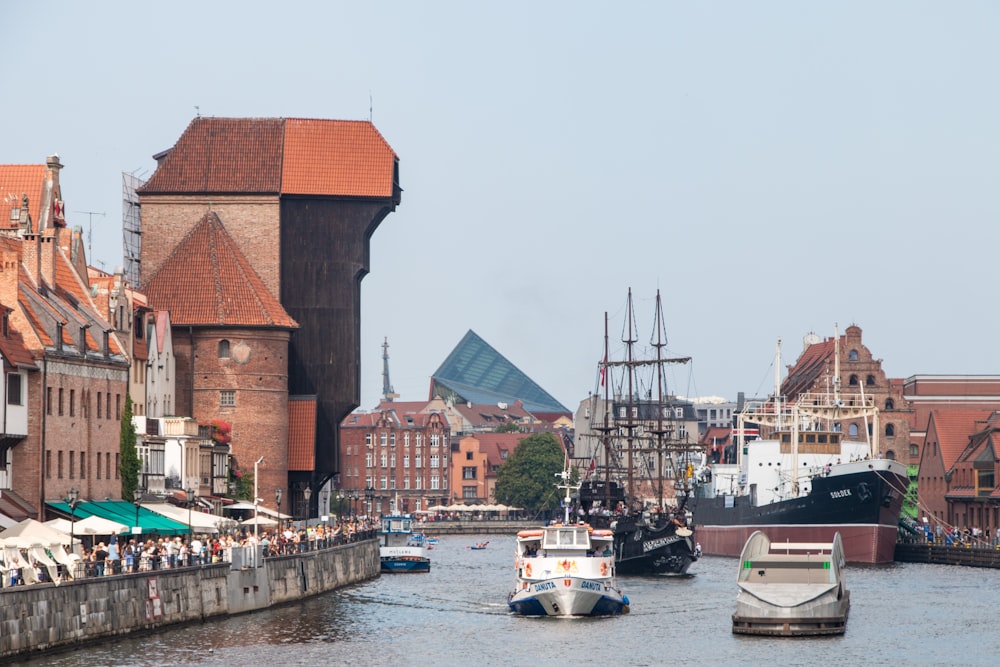 a group of boats traveling down a river next to tall buildings