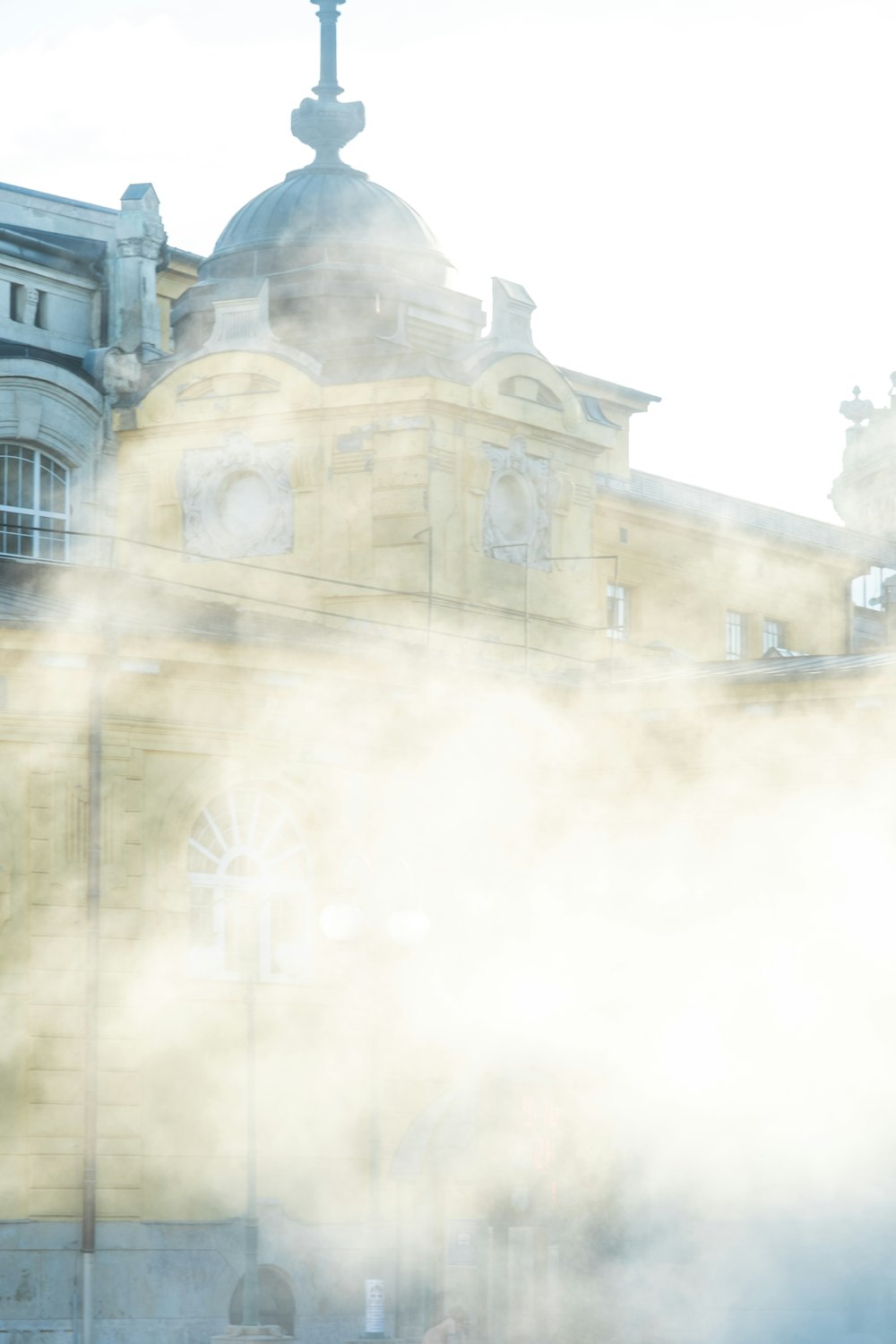 steam rises from the ground in front of a building