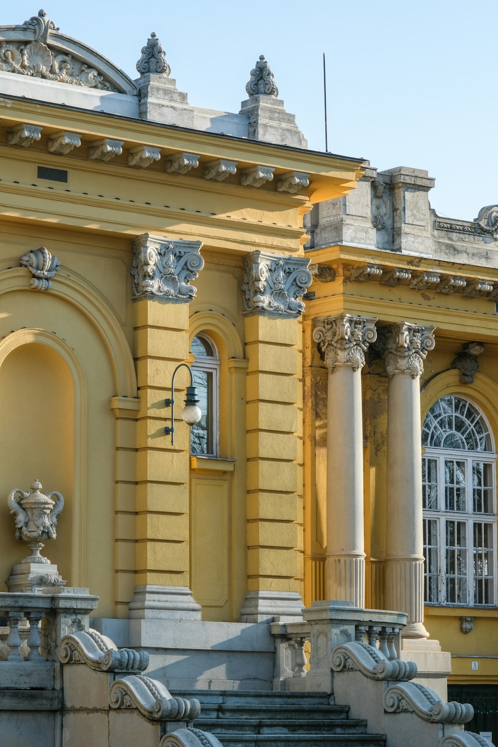 a large yellow building with columns and a clock