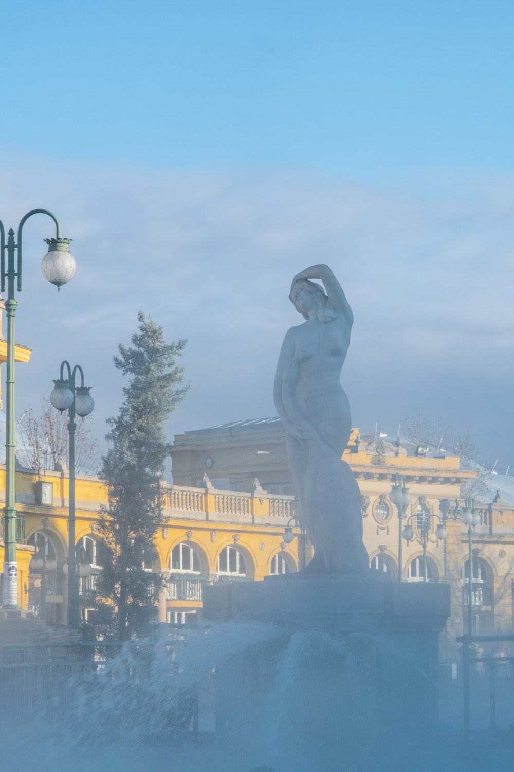 a statue of a woman in front of a yellow building