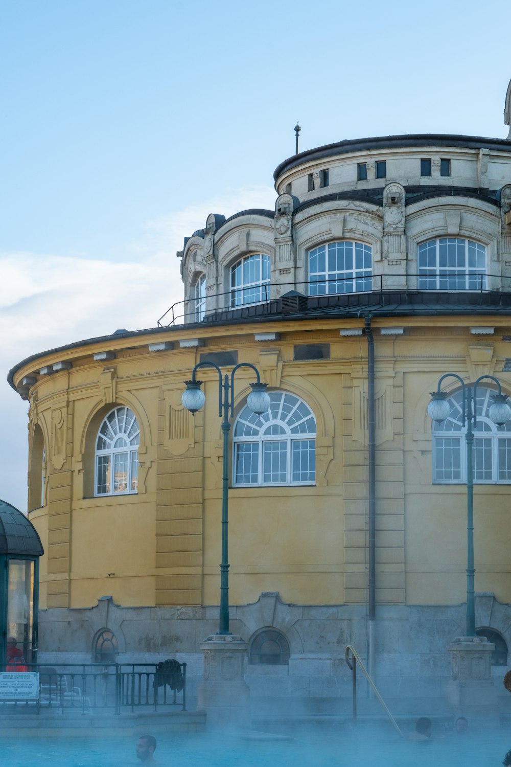 a large yellow building with a blue pool in front of it