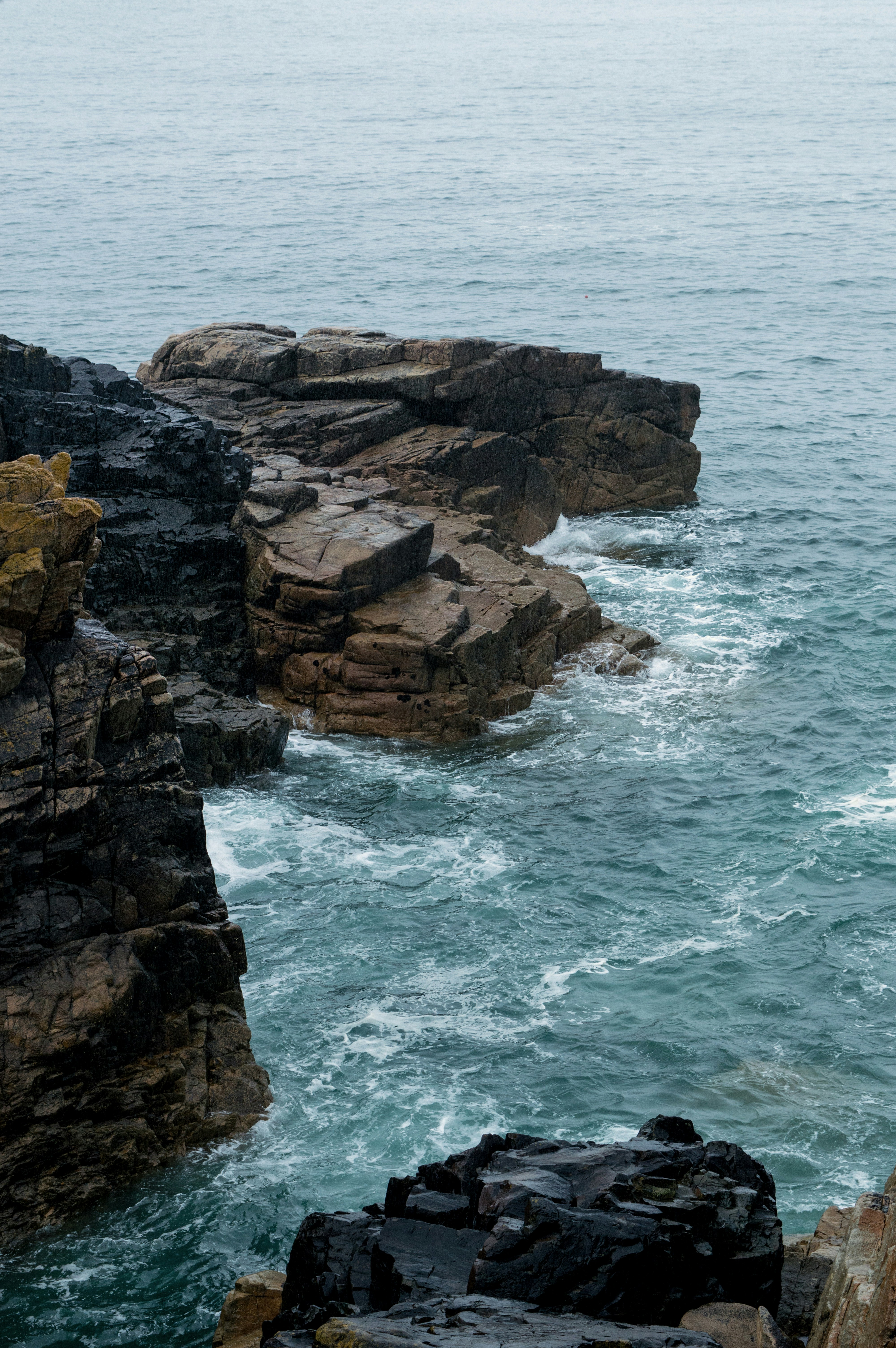 a person sitting on a rock near the ocean