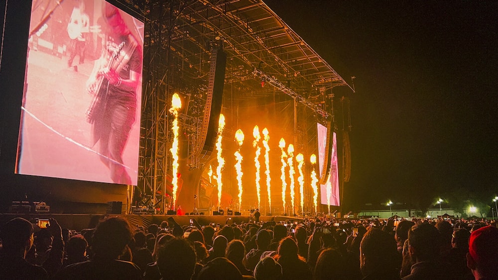 a crowd of people watching a concert on a large screen