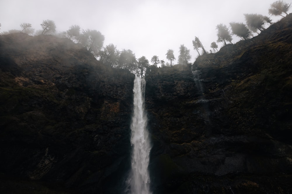 a very tall waterfall in the middle of a forest