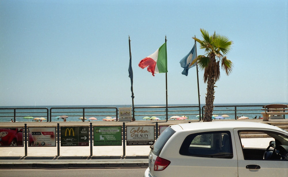 a white car driving down a street next to a beach