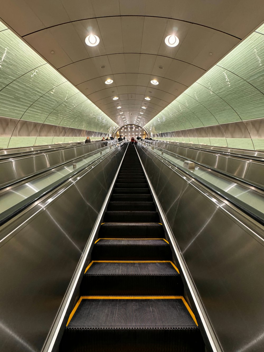 una escalera mecánica en una estación de metro con gente en ella
