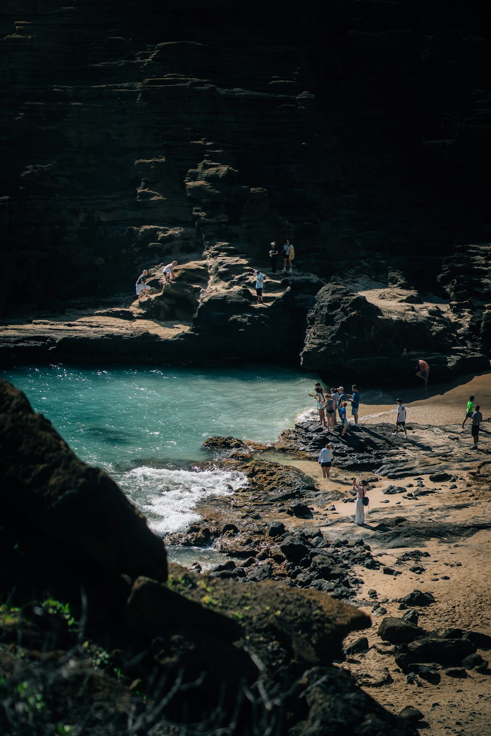 Un grupo de personas de pie en una playa junto a un cuerpo de agua