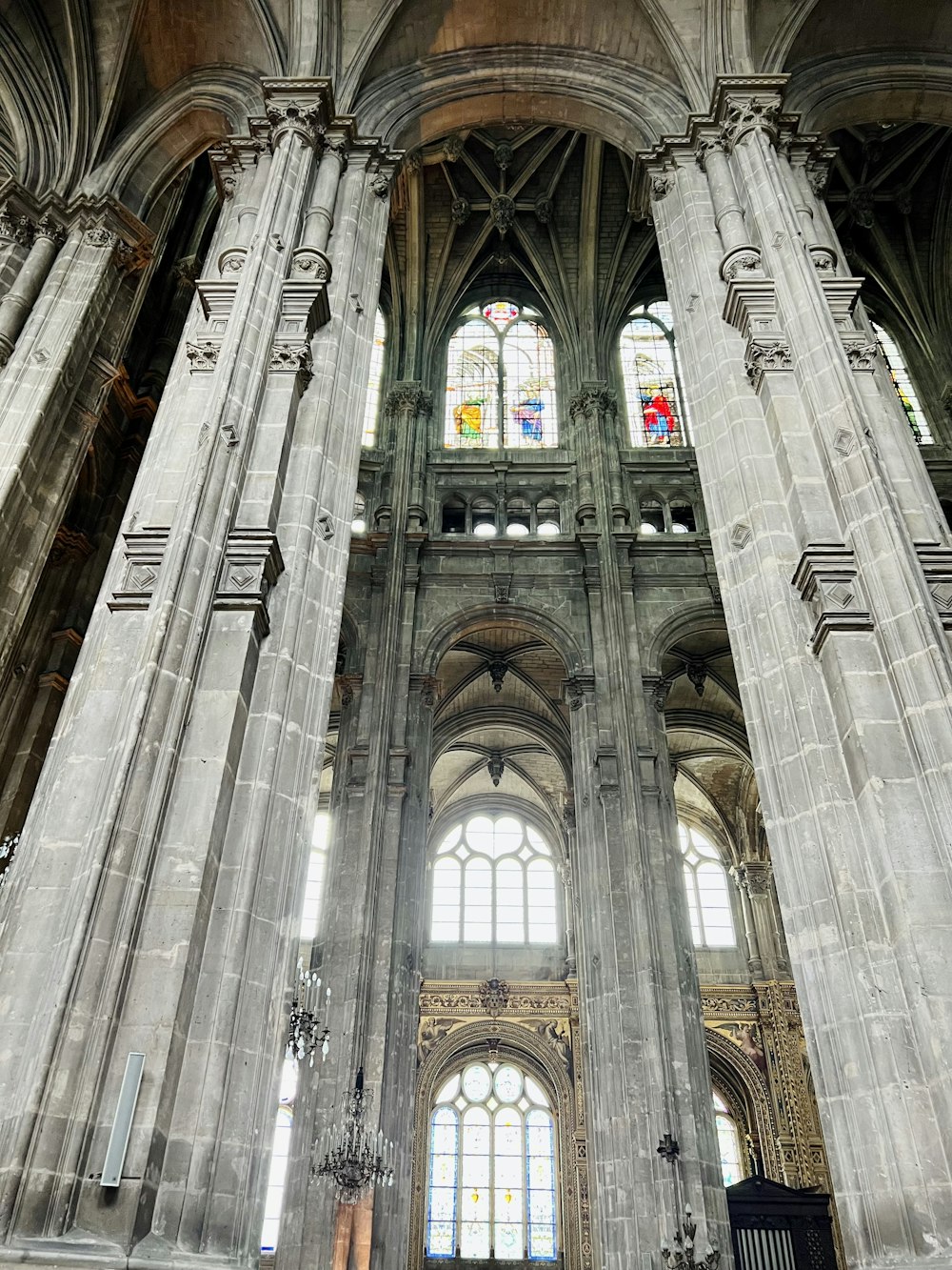 the interior of a cathedral with columns and stained glass windows