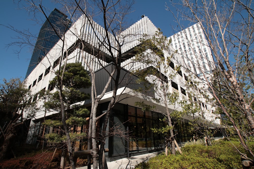 a tall white building surrounded by trees and bushes