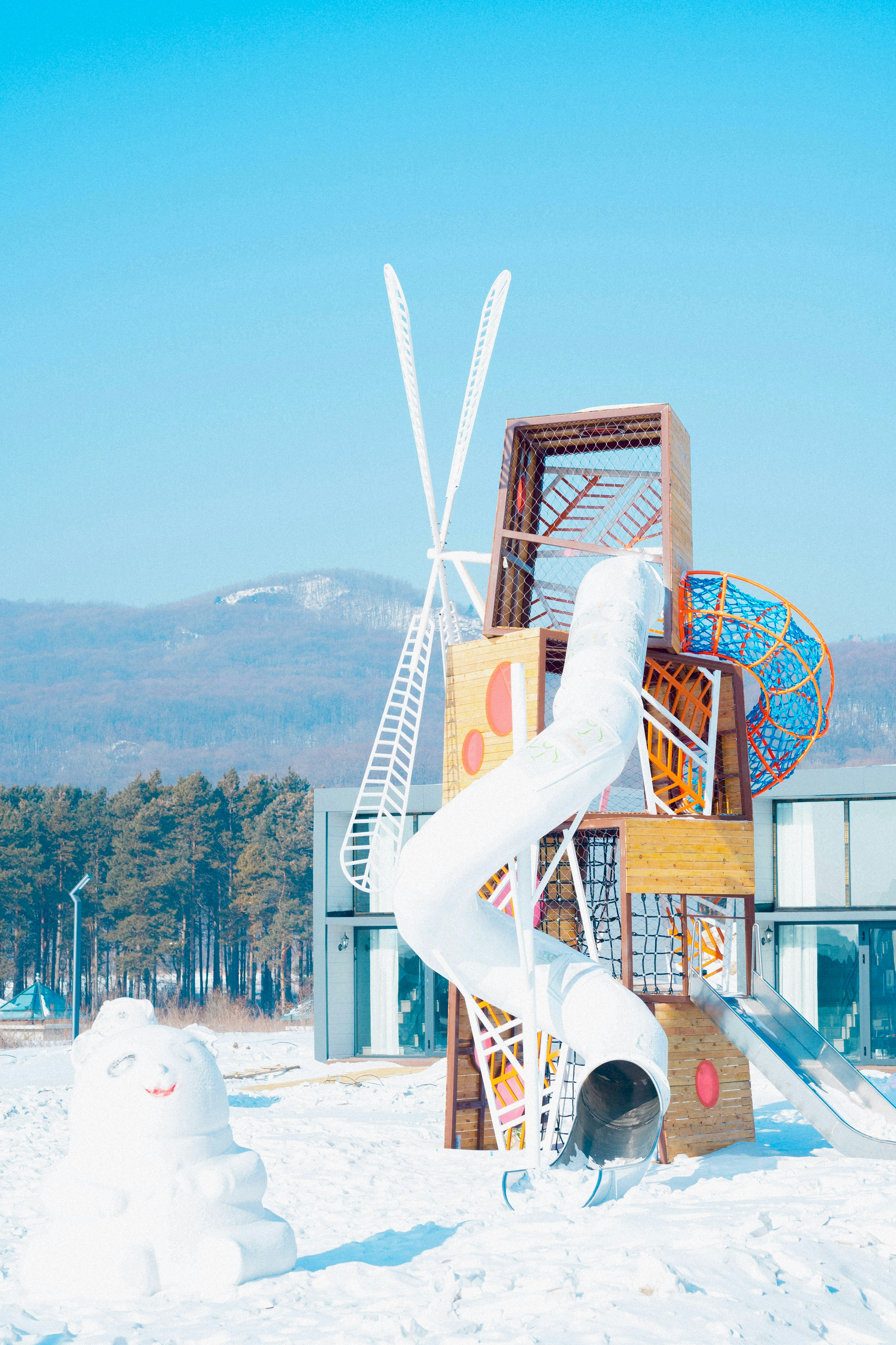 a snowman is standing in front of a building with a slide