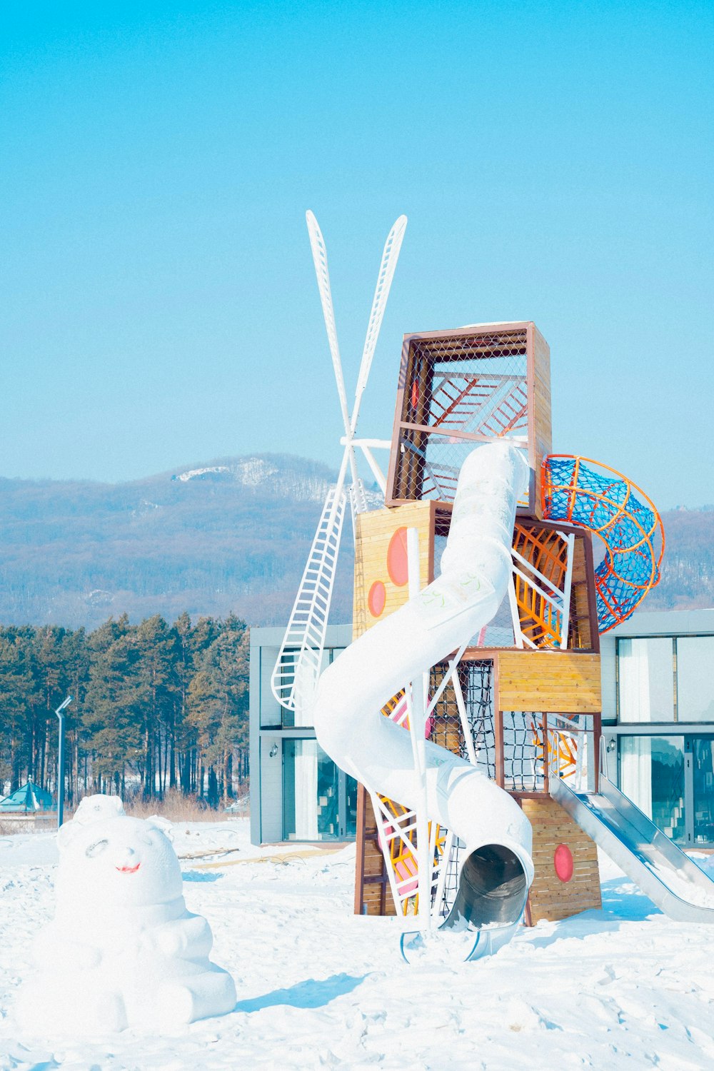 a snowman is standing in front of a building with a slide