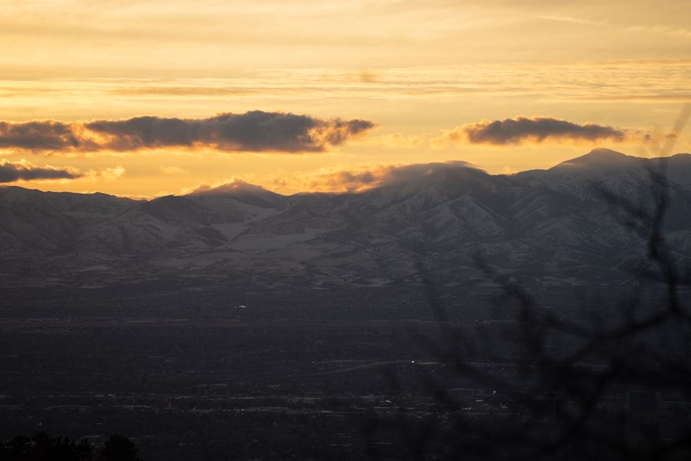 the sun is setting over the mountains in the distance