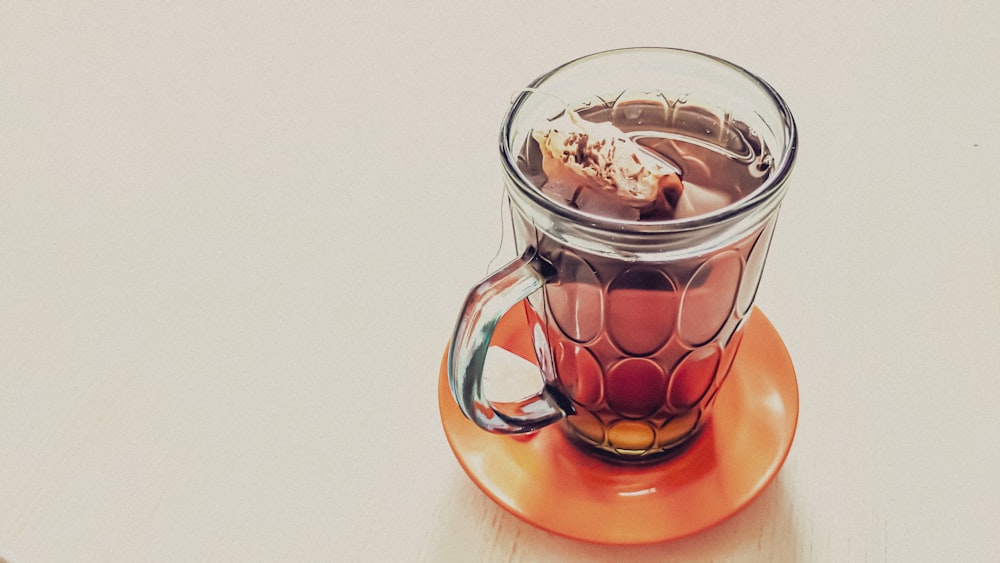 a glass cup filled with liquid on top of an orange saucer