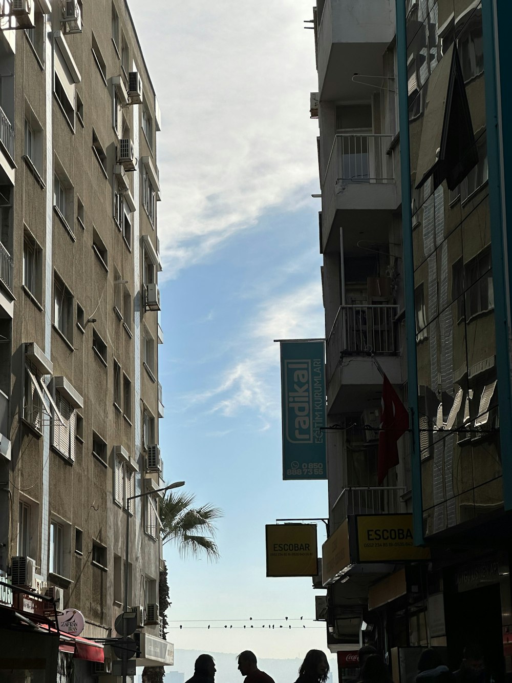 a group of people walking down a street next to tall buildings