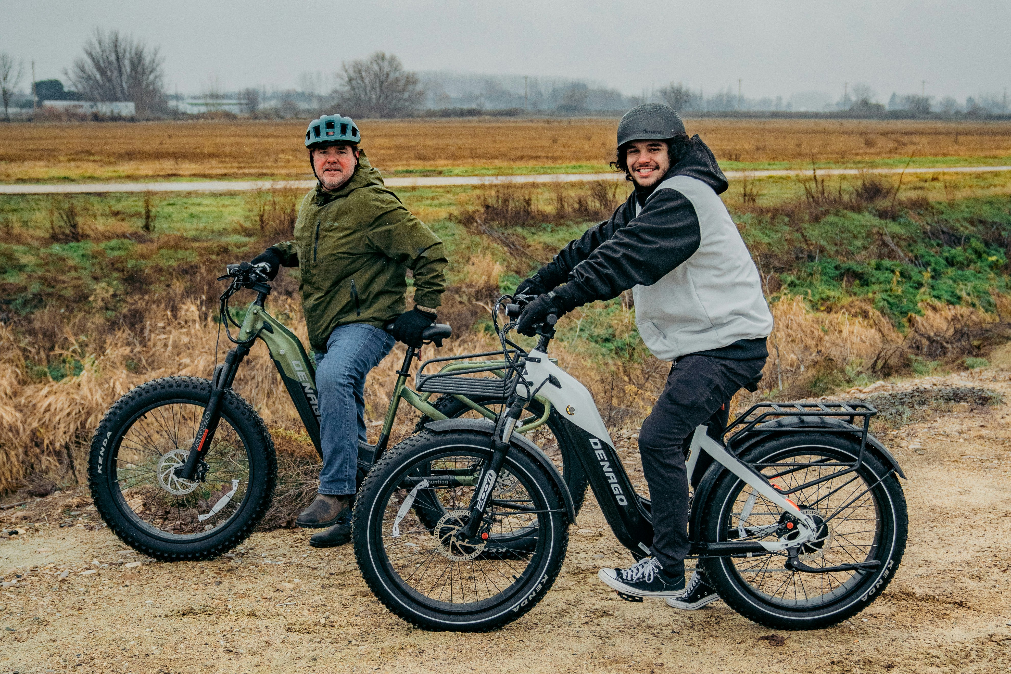 A couple of men riding bikes down a dirt road photo – Free Grey Image ...