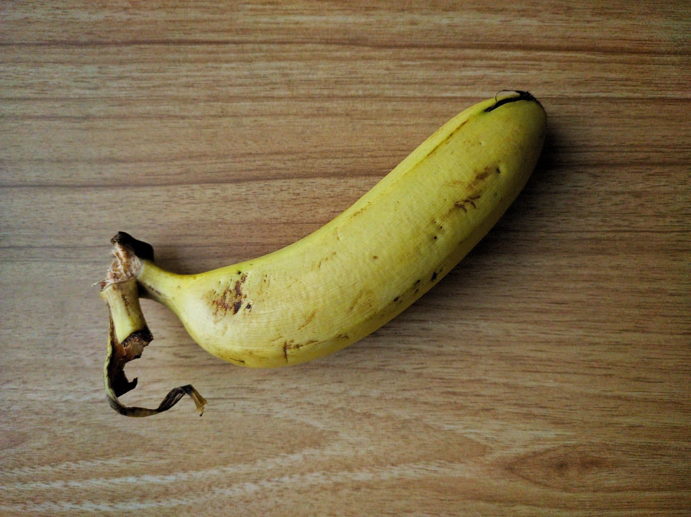 un plátano maduro sentado encima de una mesa de madera
