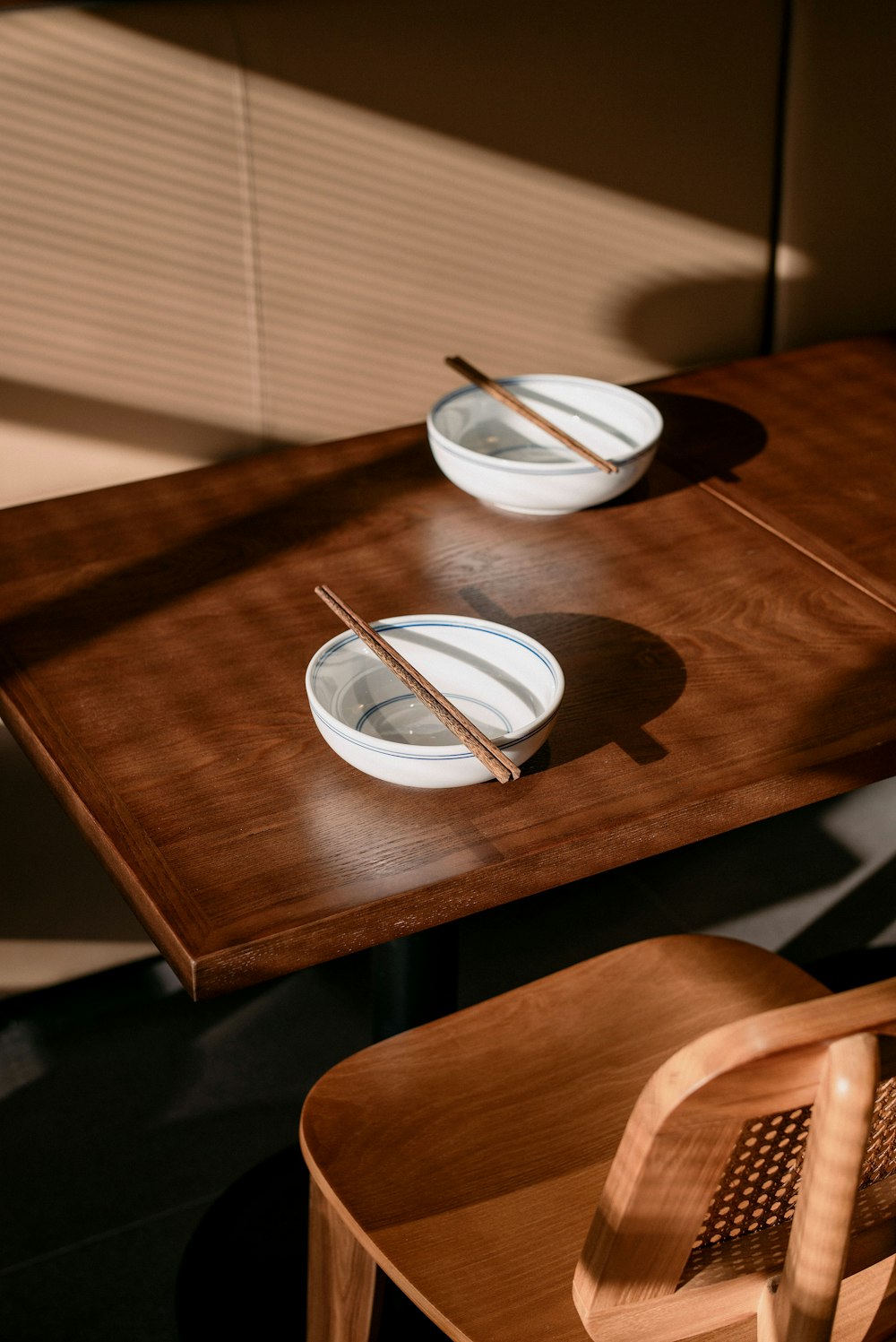 a wooden table with two plates and chopsticks on it