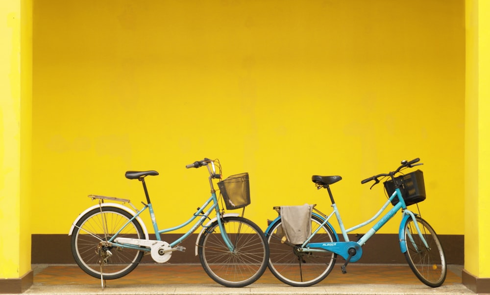 two bikes parked next to each other in front of a yellow wall