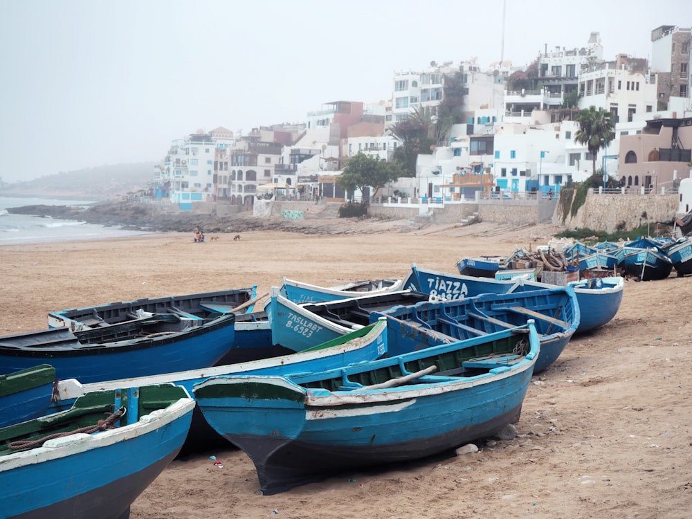 a group of blue boats sitting on top of a sandy beach