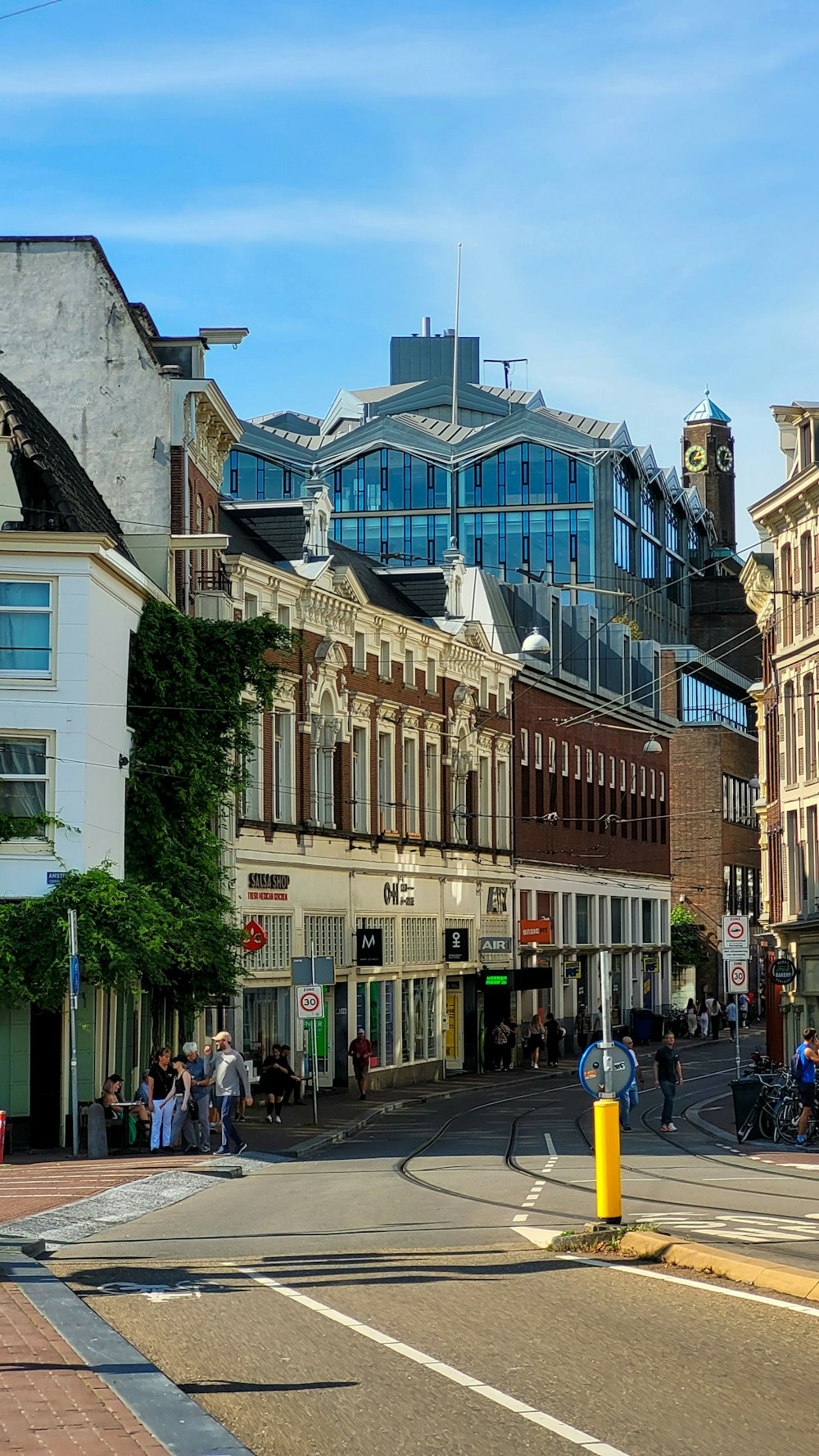 a group of people walking down a street next to tall buildings