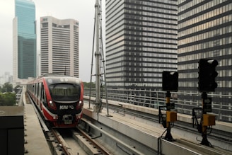 a red train traveling down train tracks next to tall buildings