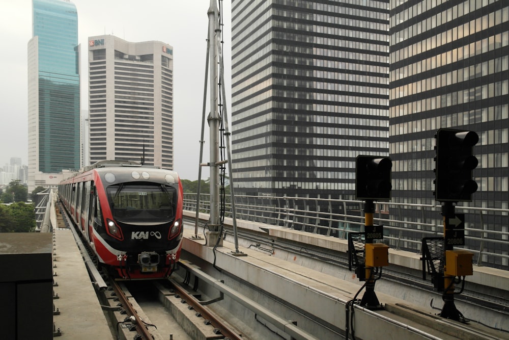 a red train traveling down train tracks next to tall buildings