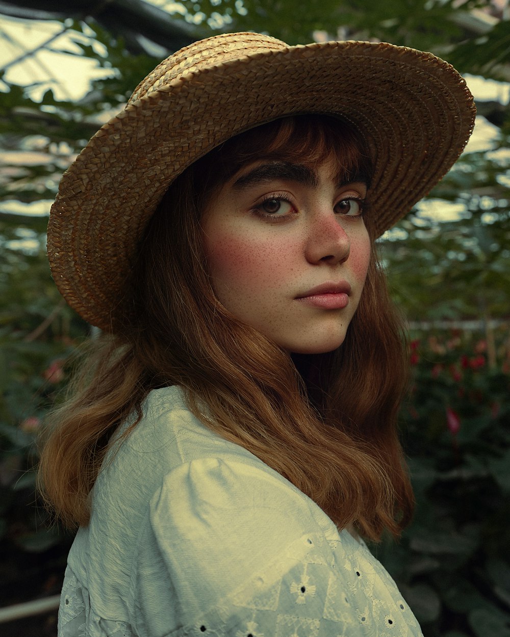una donna che indossa un cappello di paglia in una serra