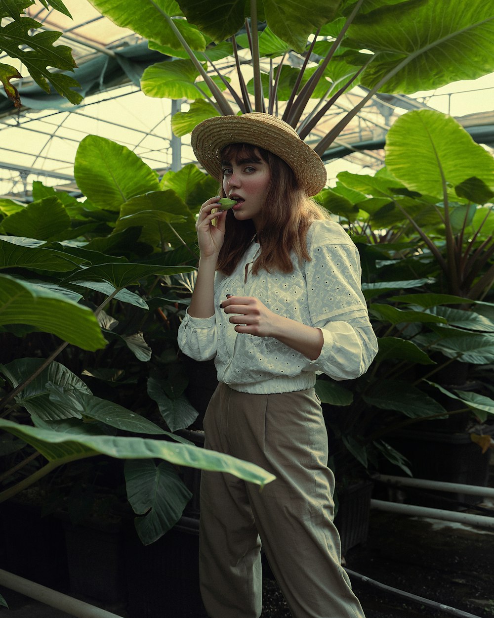 a woman standing in a greenhouse smoking a cigarette