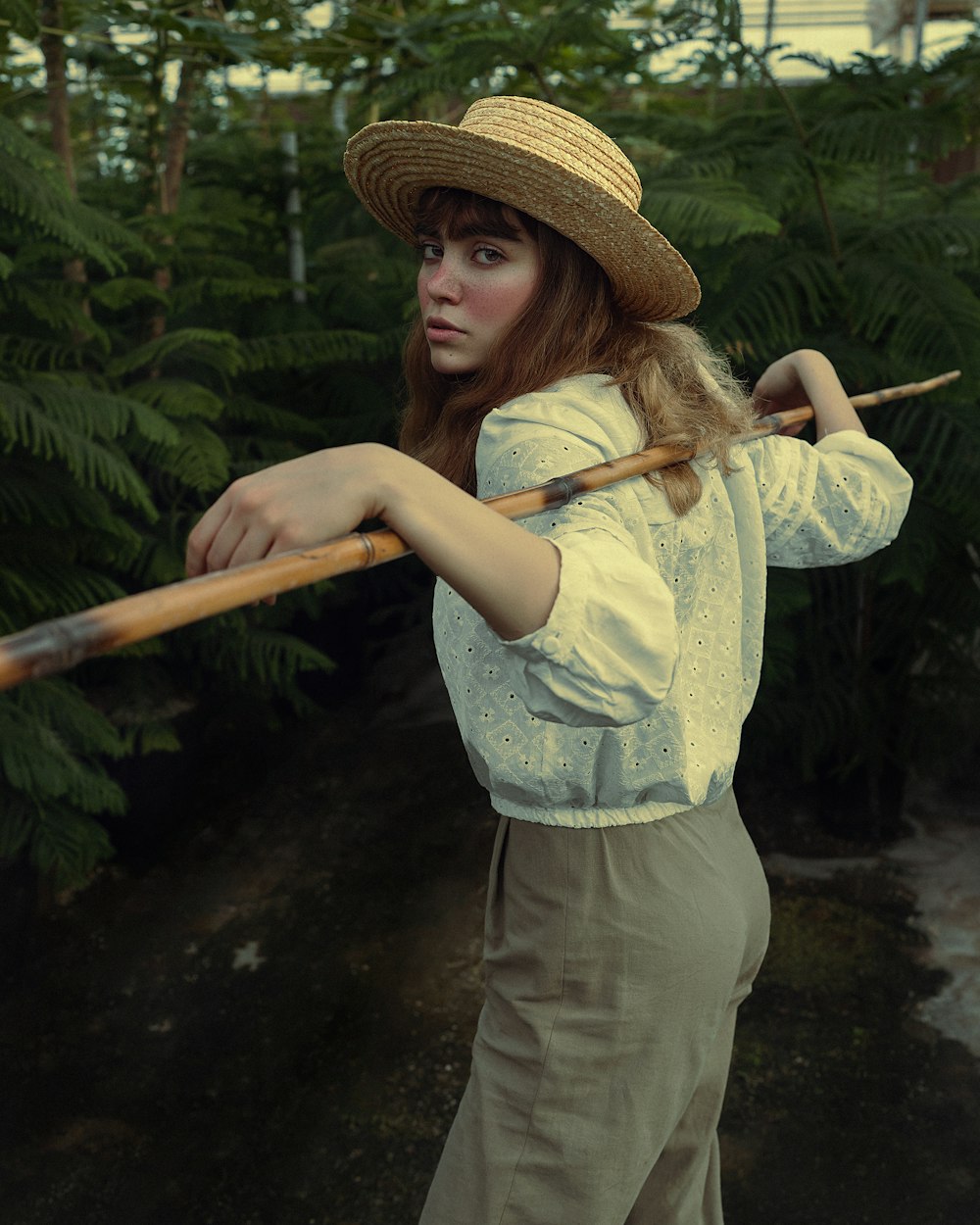 a woman in a straw hat holding a stick