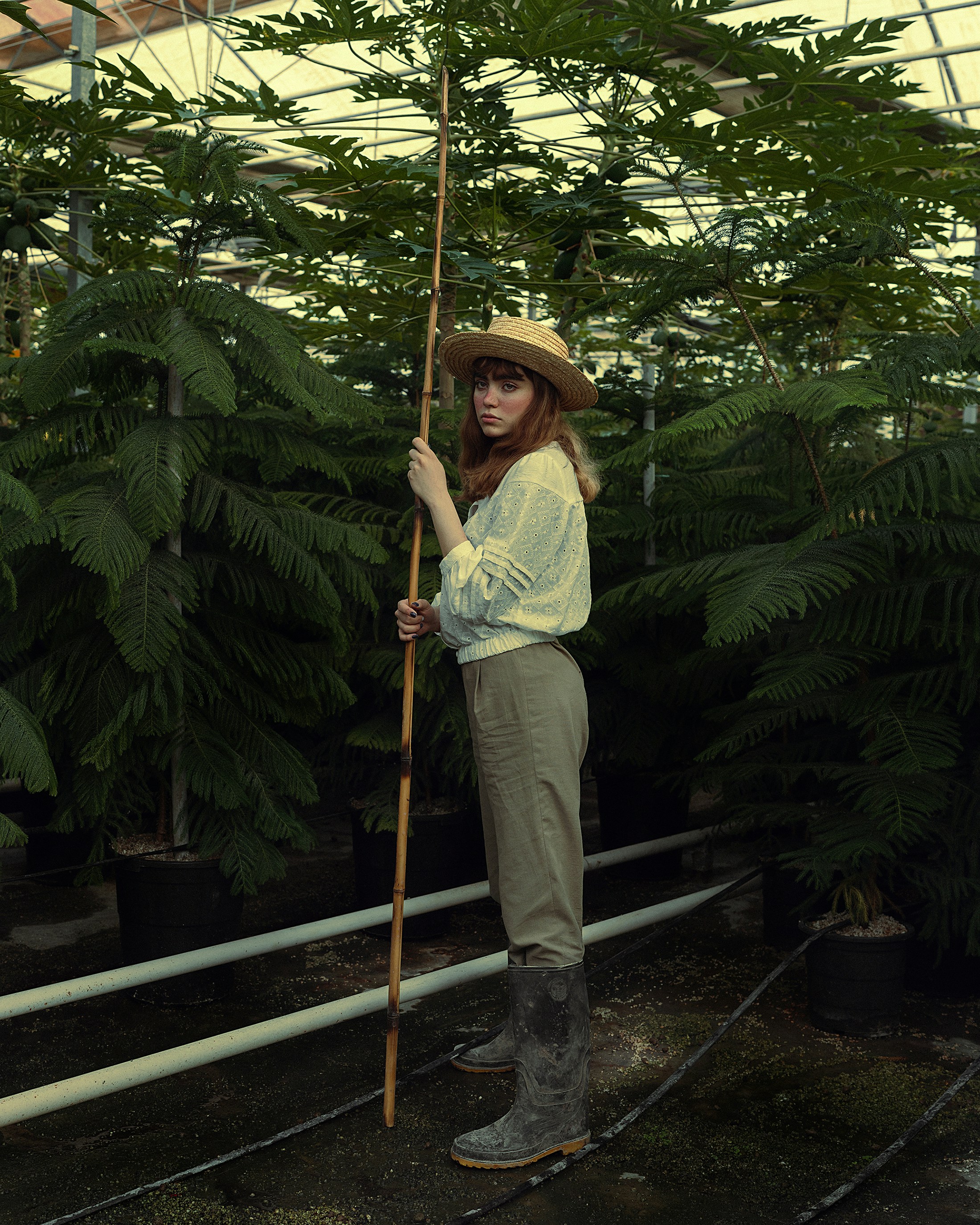 a woman standing in a greenhouse holding a stick
